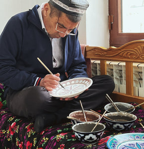 Bayali's artisan Tadzaliev painting on ceramics
